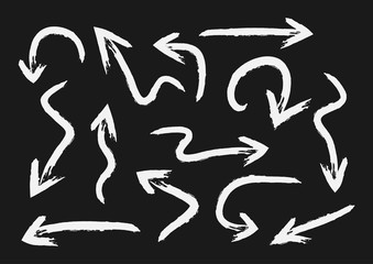 Set of white arrows painted with a brush. Grunge. Isolated on black background.