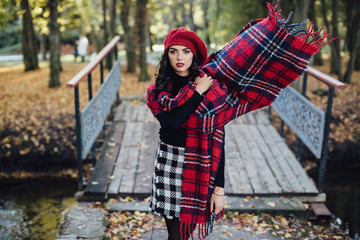 Beautiful happy girl in red hat and scarf walking in the autumn park