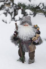 Doll of Santa Claus with gifts on snow