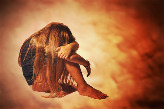 Bambina triste rannicchiata su se stessa