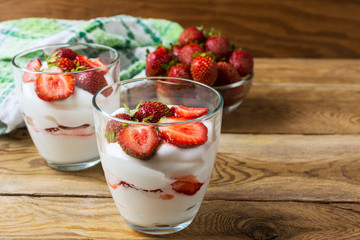 Summer dessert with whipped cream and strawberry on wooden backg
