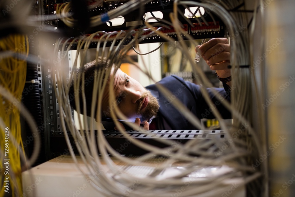 Poster technician talking on mobile phone while checking cables