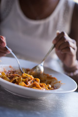 a young African American woman eating pasta