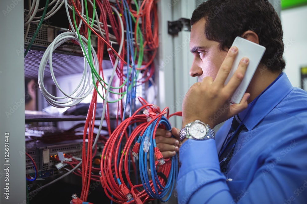 Poster technician talking on mobile phone while checking cables
