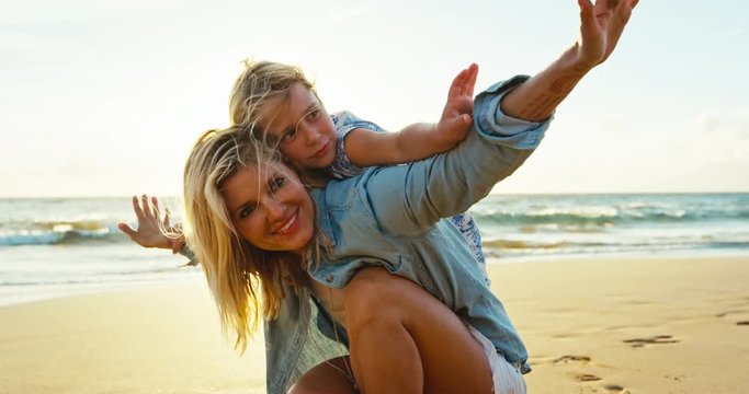 Mother and daughter having fun playing on the beach at sunset
