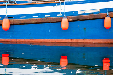 Buoys on blue fishing boat reflected in water