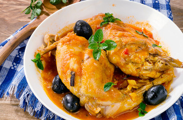 Stewed rabbit legs with black olives and herbs leaves.