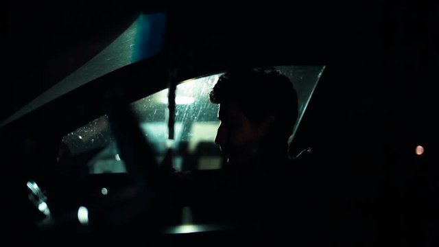 Profile of a man in a car on a dark night. Noir style