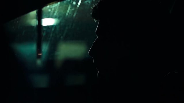 Profile of a man in a car on a dark night. Noir style