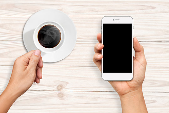 Hands holding a cup of coffee and White Smart phone