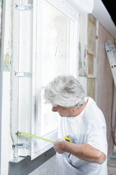 Mason measuring up a window