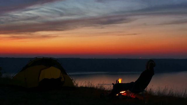 
4K  Tent,bonfire, sunrise and man silhouette near lake.  
