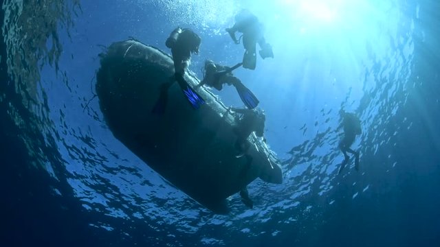 A inflatable boat (zodiac) from below with divers around.