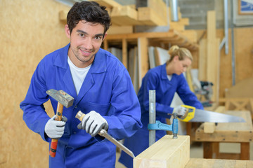 Young carpenter using hammer and chisel