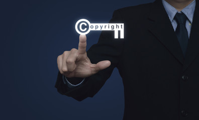 Fototapeta premium Businessman pressing copyright key icon on blue background, Copy