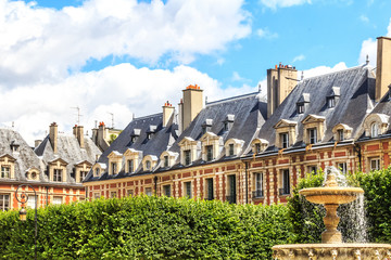 Historic buildings with fountain at the famous Place des Vosges in Paris