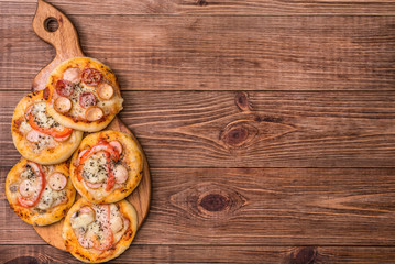 Mini pizzas on wooden board.