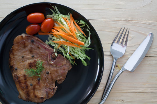 steak with salad and tomatoes on wood background