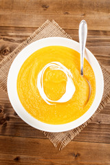 homemade pumpkin soup with cream fresh in a deep plate on jute
