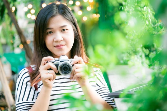 Young asian woman making photos with vintage film camera