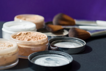 White and beige mineral powder for long lasting make up and a set of make up brushes on background