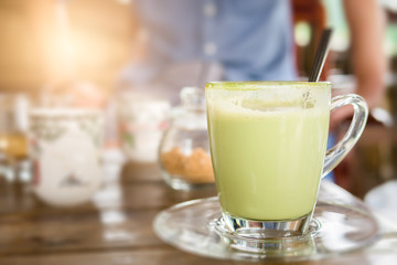 Hot green tea with milk in glass mug.