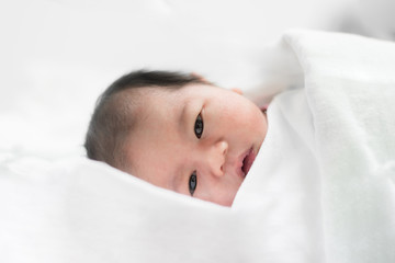 Fototapeta na wymiar Asian newborn boy sleeping over his white bed covered
