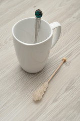 A white mug with a sugar stick and a teaspoon 