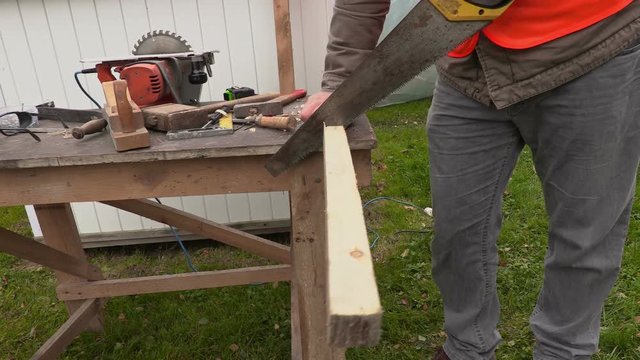 Carpenter trying to saw off wooden plank