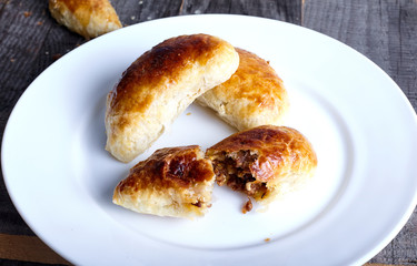 Small empanadas with meat on a white plate.