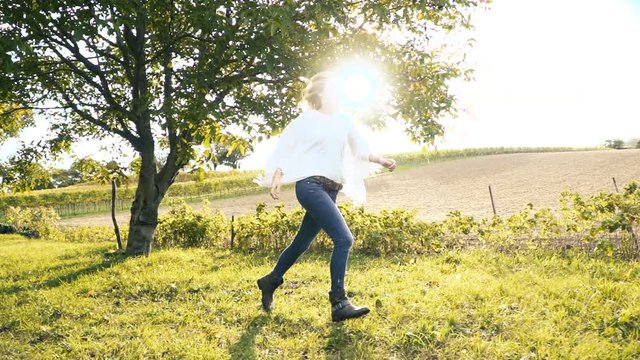 Frau am Morgen l&auml;uft &uuml;ber Wiese vor der Sonne