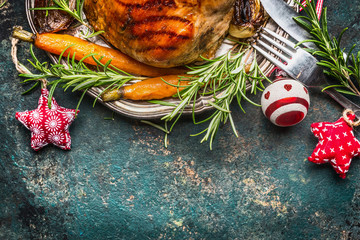 Roasted pork ham on silver plate with vegetables , cutlery  and Christmas decoration, top view,...