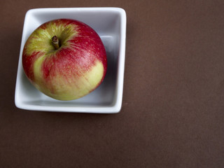 Akane apple in a bowl on brown background