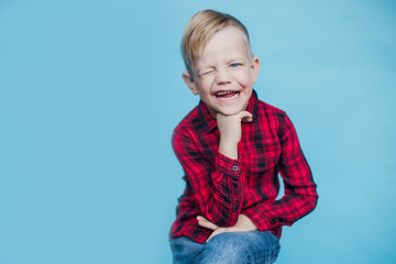 Fashionable little kid with red shirt. Fashion. Style. Studio portrait over blue background