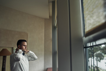 The handsome groom stands near window