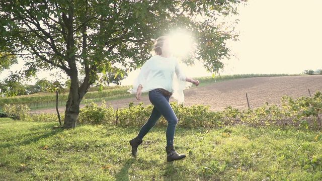 Frau am Morgen l&auml;uft &uuml;ber Wiese vor der Sonne