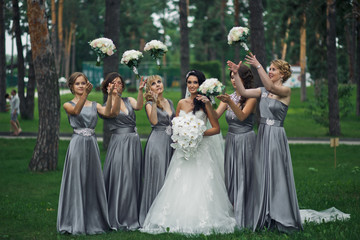 The smilling bride with bridesmaids in the park