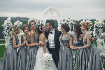 The charming bridesmaids with brides stand near statuettes