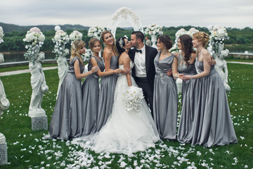 The charming bridesmaids with brides stand near statuettes
