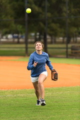 Young woman softball player running to catch ball