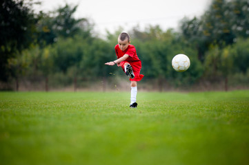 Little football player shooting the ball
