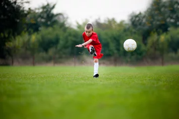 Foto op Plexiglas Little football player shooting the ball © marritch