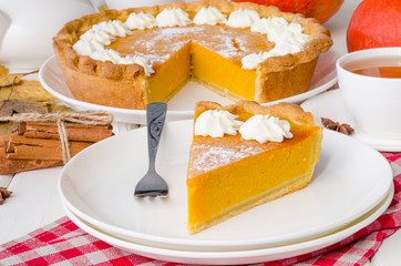 Festive homemade delicious pumpkin pie with whipped cream made for Thanksgiving and halloween.