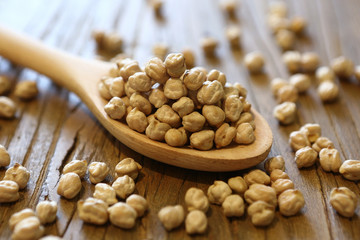Dry and uncooked chickpeas in spoon and scattered