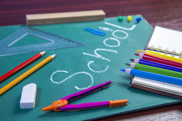 School supplies and accessory on green school table.