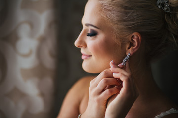 Obraz premium Daydreaming bride touches her earring delcately standing behind