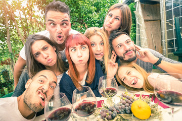 Best friends taking selfie outdoor with back lighting - Happy youth concept with young people having fun together drinking wine - Cheer and friendship at grape harvest time - Soft desaturated filter