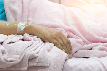 saline water line at the hand of patient on bed in hospital room