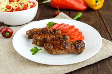 Juicy grilled rolls of minced meat wrapped in bacon with fresh tomato and a light salad of Chinese cabbage and bell pepper.