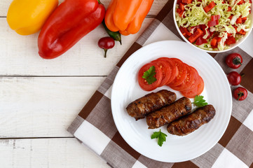 Juicy grilled rolls of minced meat wrapped in bacon with fresh tomato and a light salad of Chinese cabbage and bell pepper.